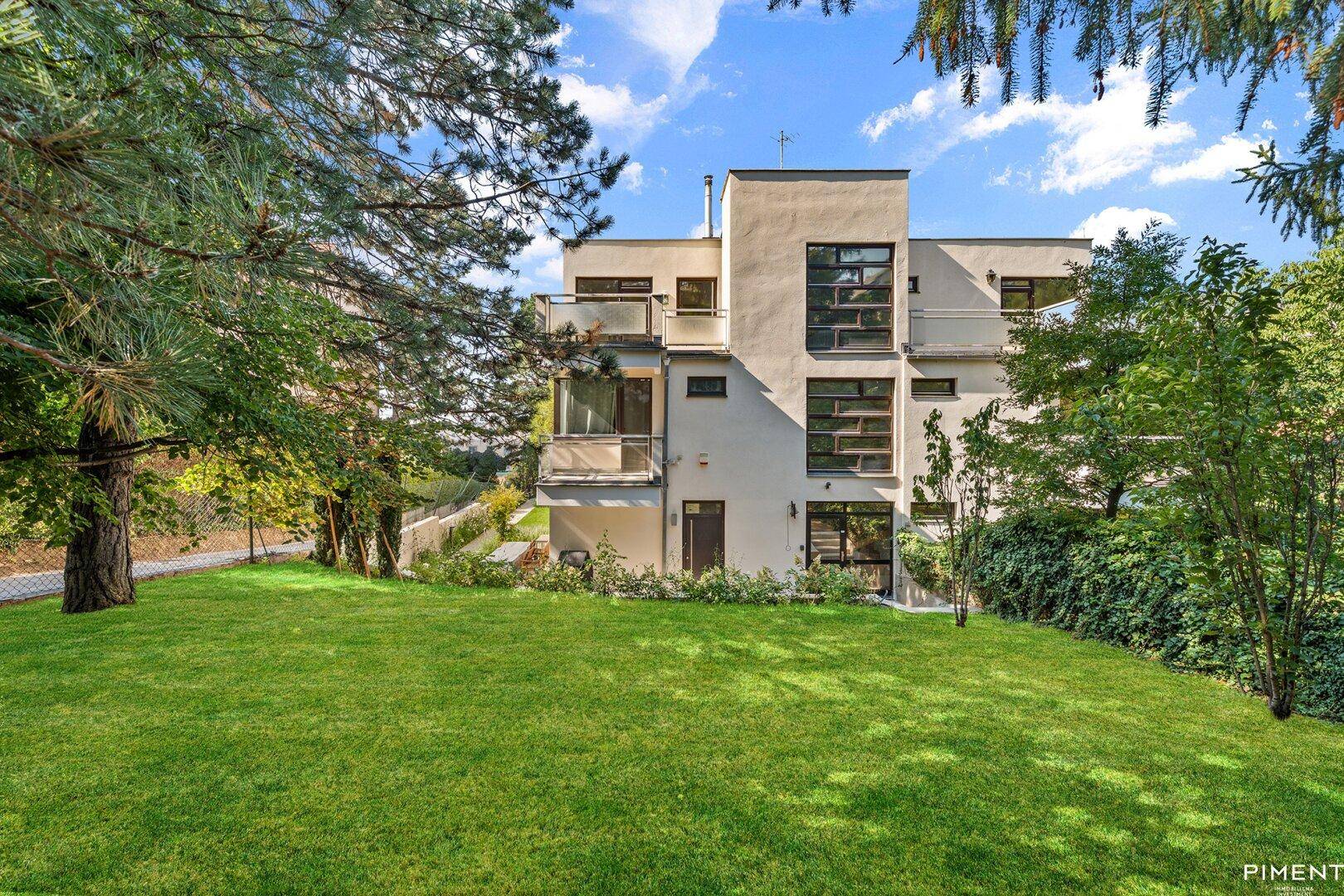 Modernes Mehrfamilienhaus mit großem Garten, Rasenfläche und mehreren Balkonen.