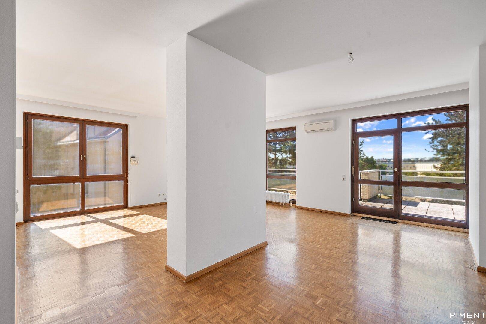 Heller, leerer Wohnraum mit Parkettboden, Klimaanlage und Zugang zu einer Terrasse.