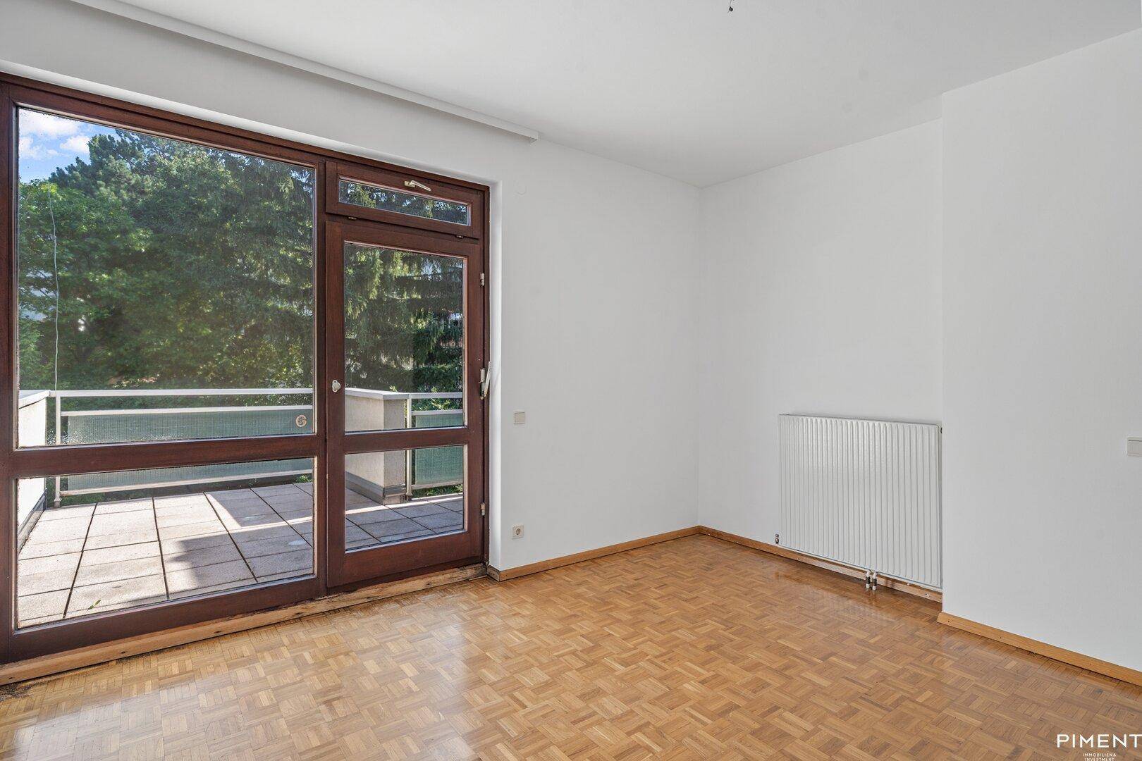 Helles Zimmer mit Parkettboden und direktem Zugang zu einer Außenterrasse.