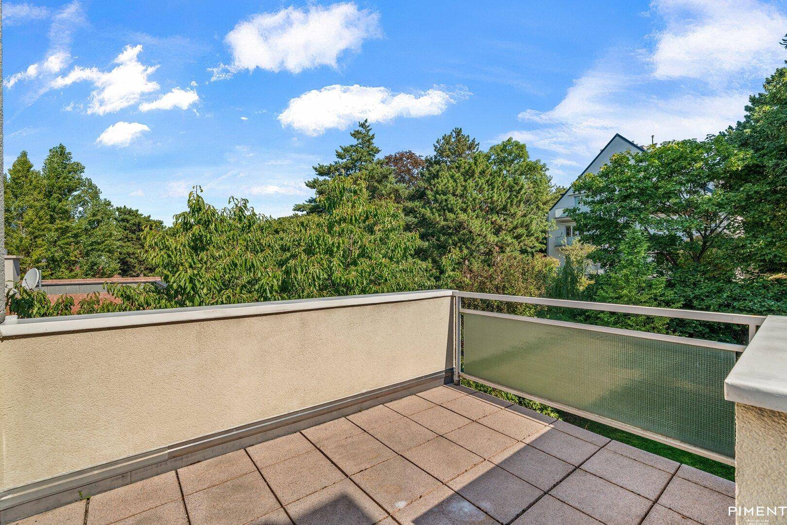 Terrasse mit Fliesenboden und grüner Aussicht auf Bäume und die Nachbarschaft.