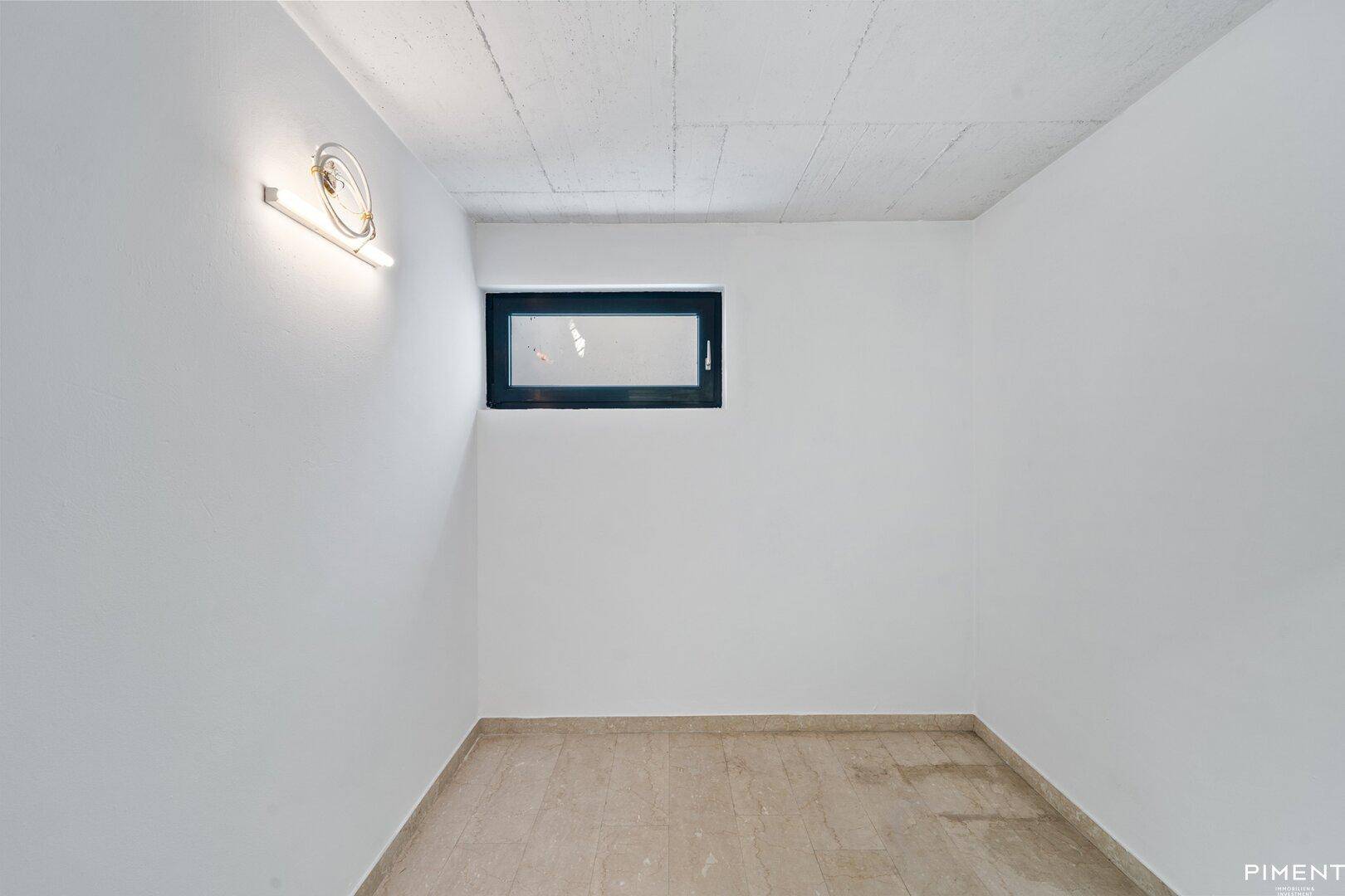 Einfacher Kellerraum mit kleinem, hochgelegenem Fenster und Fliesenboden.