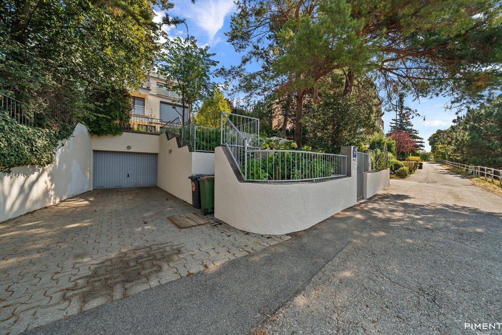 Zufahrt zur Tiefgarage mit Treppenaufgang zum Gebäude und Mülltonnen.