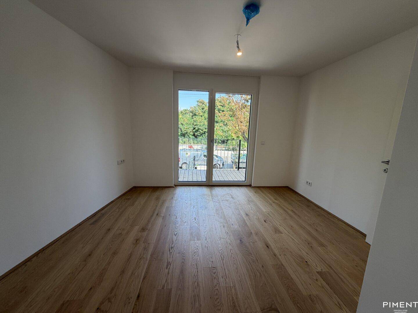 Helles Schlafzimmer mit Holzboden und direktem Zugang zum Balkon, bietet viel Tageslicht.