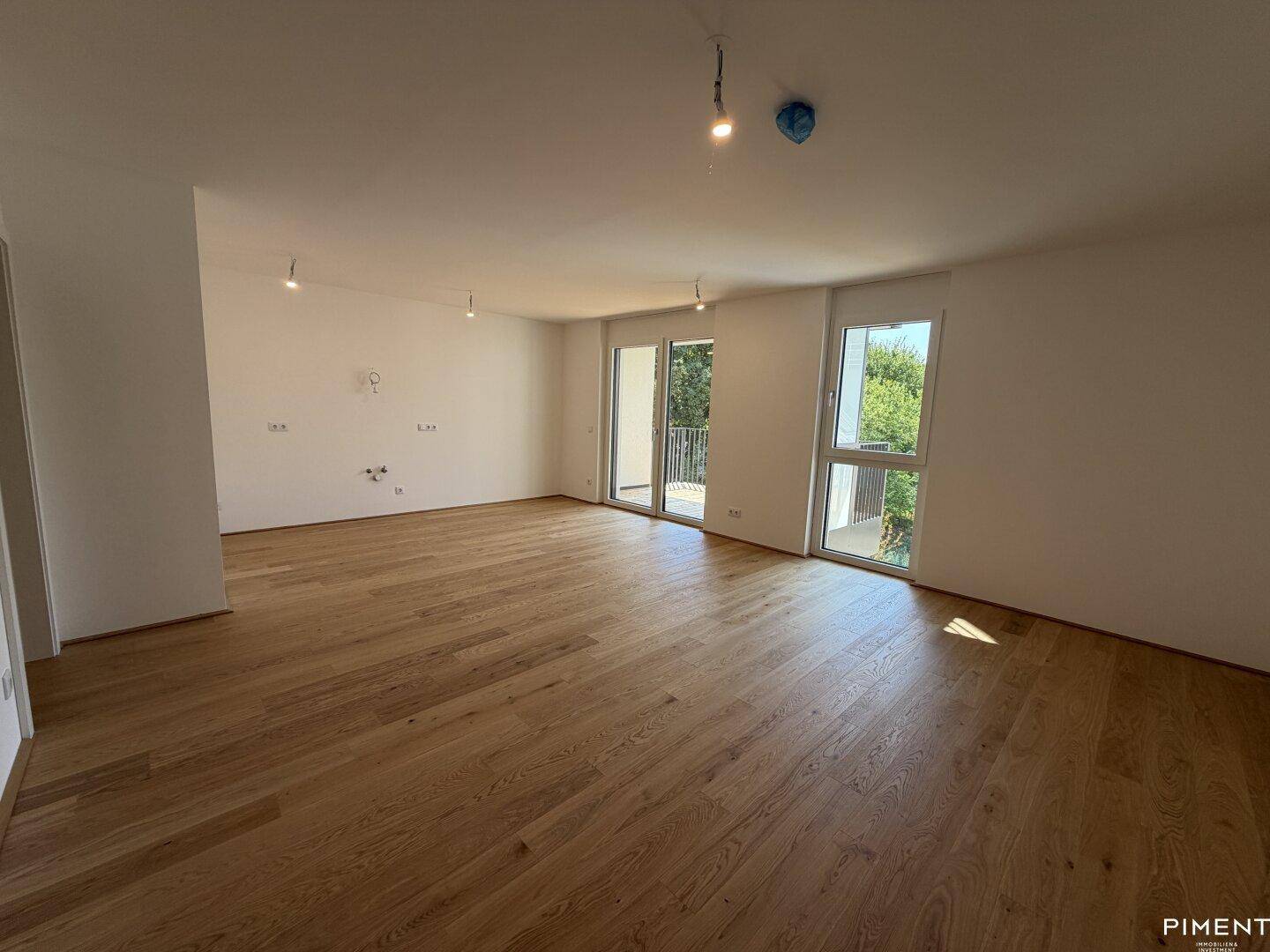 Heller, geräumiger Wohnbereich mit Eichenparkett und Zugang zu einem Balkon, bereit für individuelle Gestaltung.