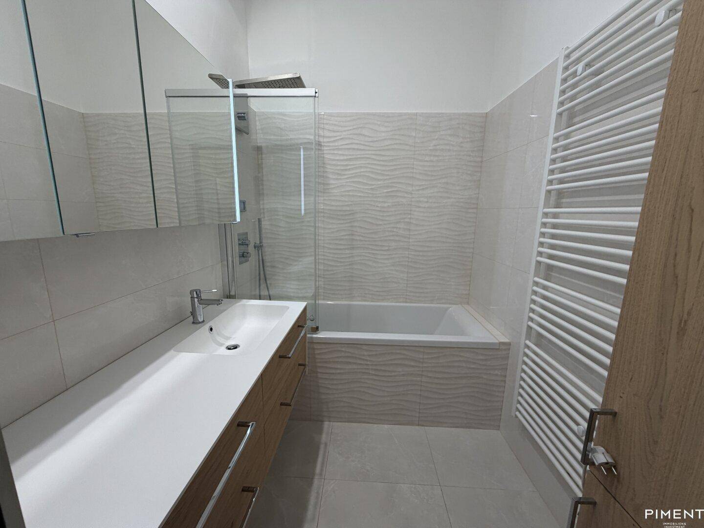 Modernes Badezimmer mit Badewanne, Dusche, Einzelwaschbecken und beheiztem Handtuchhalter.