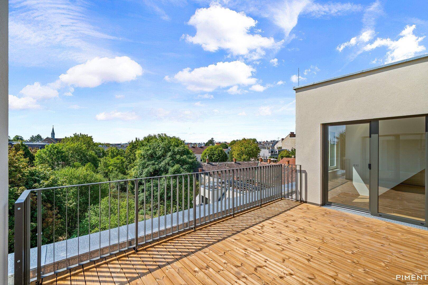 Geräumige Dachterrasse mit Holzboden und weitem Blick über die Stadt und grüne Umgebung.