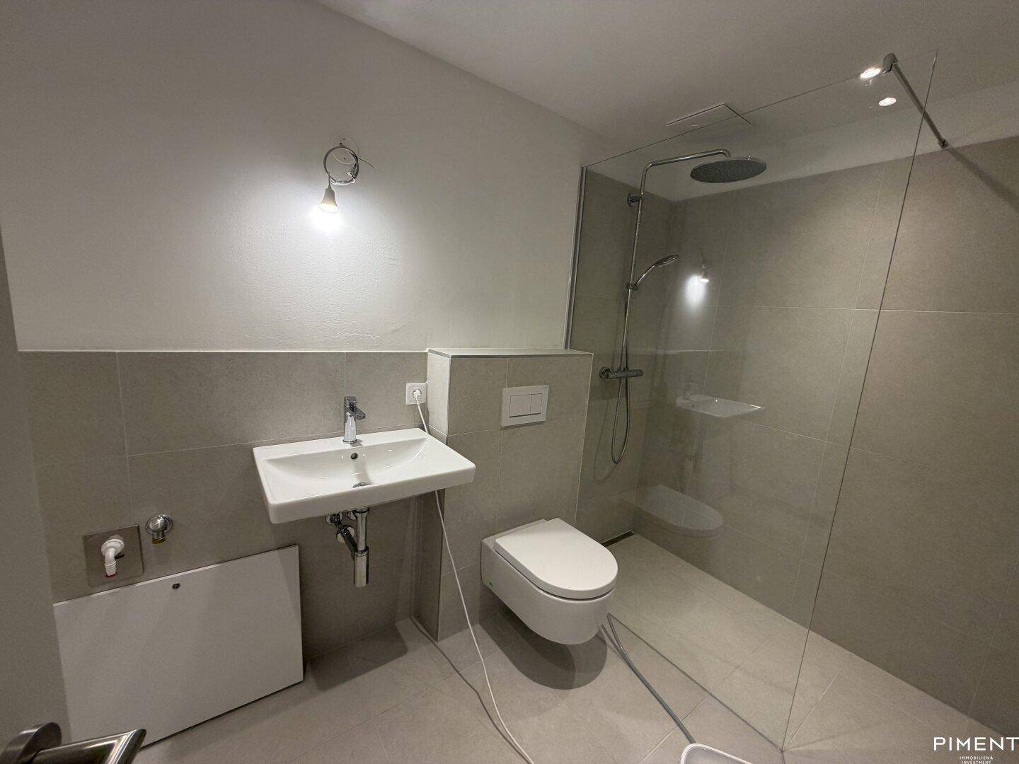 Helles Badezimmer mit moderner begehbarer Dusche, Einzelwaschbecken und Wand-WC.