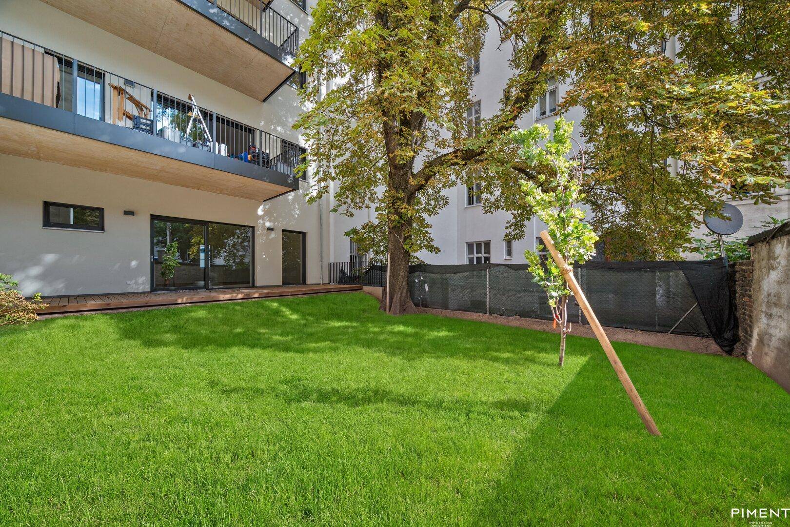 Gepflegter Rasenbereich hinter dem Gebäude mit Blick auf die Balkone der Wohnungen.