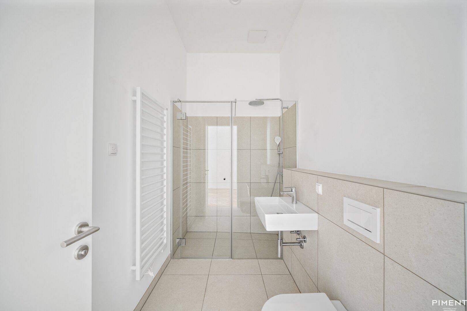 Modernes Badezimmer mit ebenerdiger Dusche, Wand-WC und beheiztem Handtuchhalter.