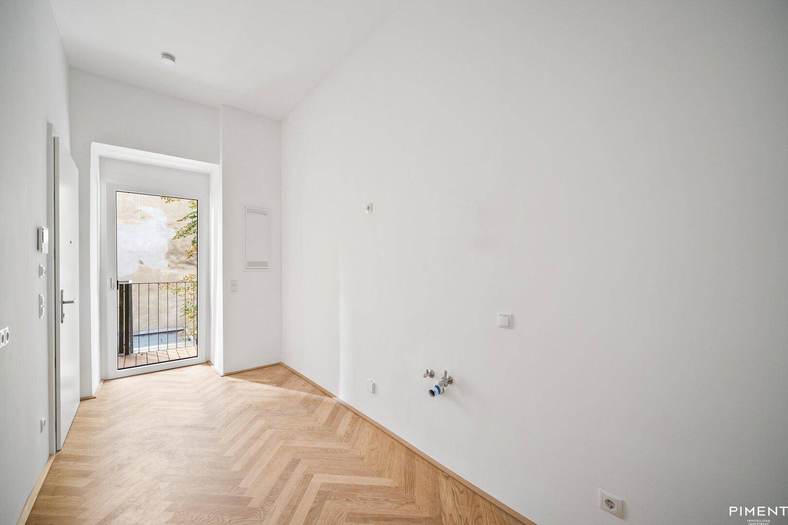 Heller Flur mit Fischgrätparkett und Zugang zu einem französischen Balkon.