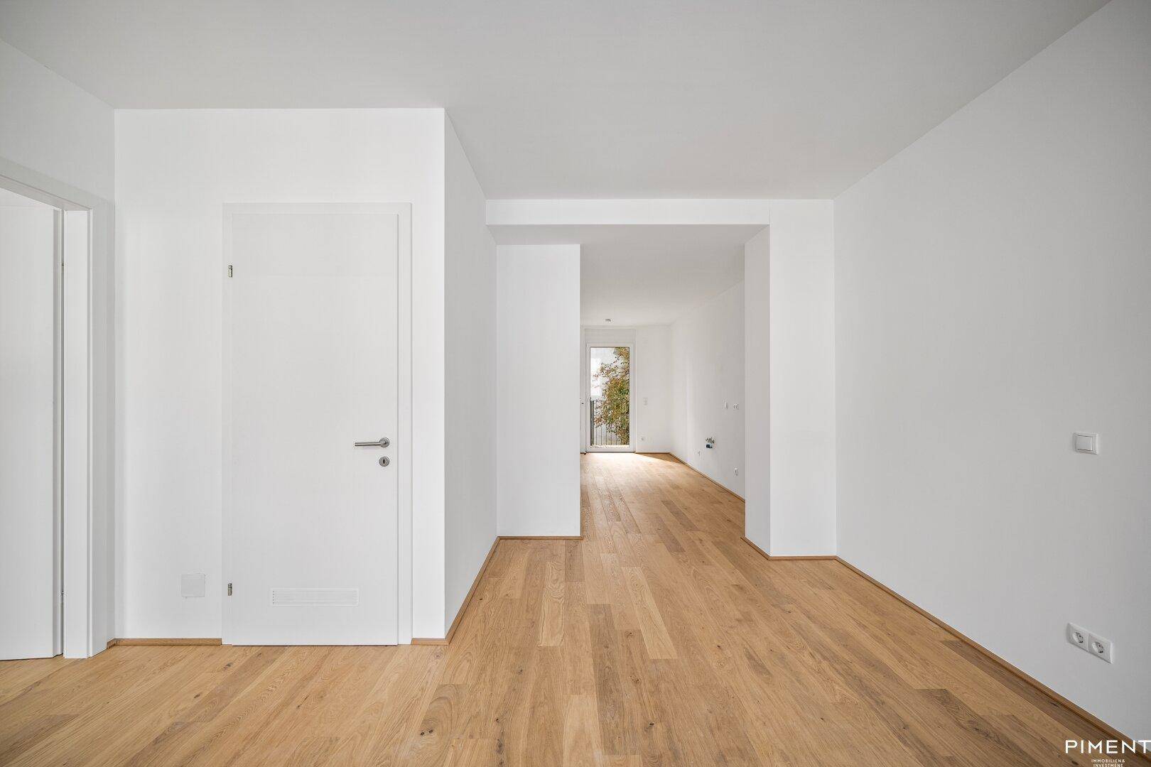 Heller Flur mit Holzboden und einem Durchgang, der zu einem Balkon führt.