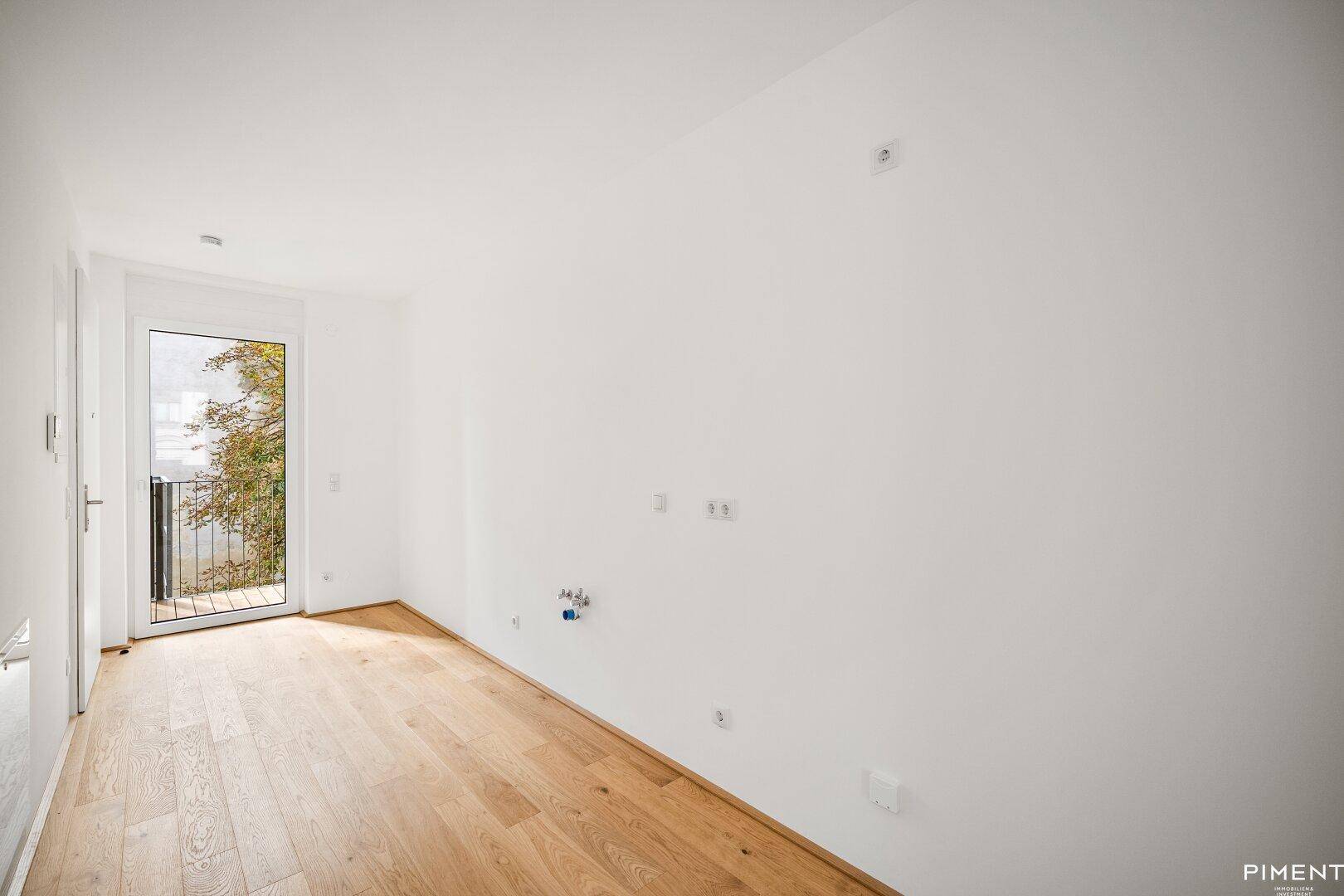 Helles Zimmer mit Holzboden und einer Tür, die direkten Zugang zu einem Außenbereich bietet.
