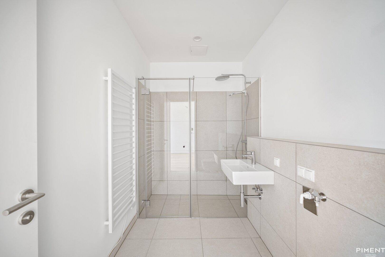 Modernes Badezimmer mit begehbarer Dusche, Waschbecken und beheiztem Handtuchhalter.