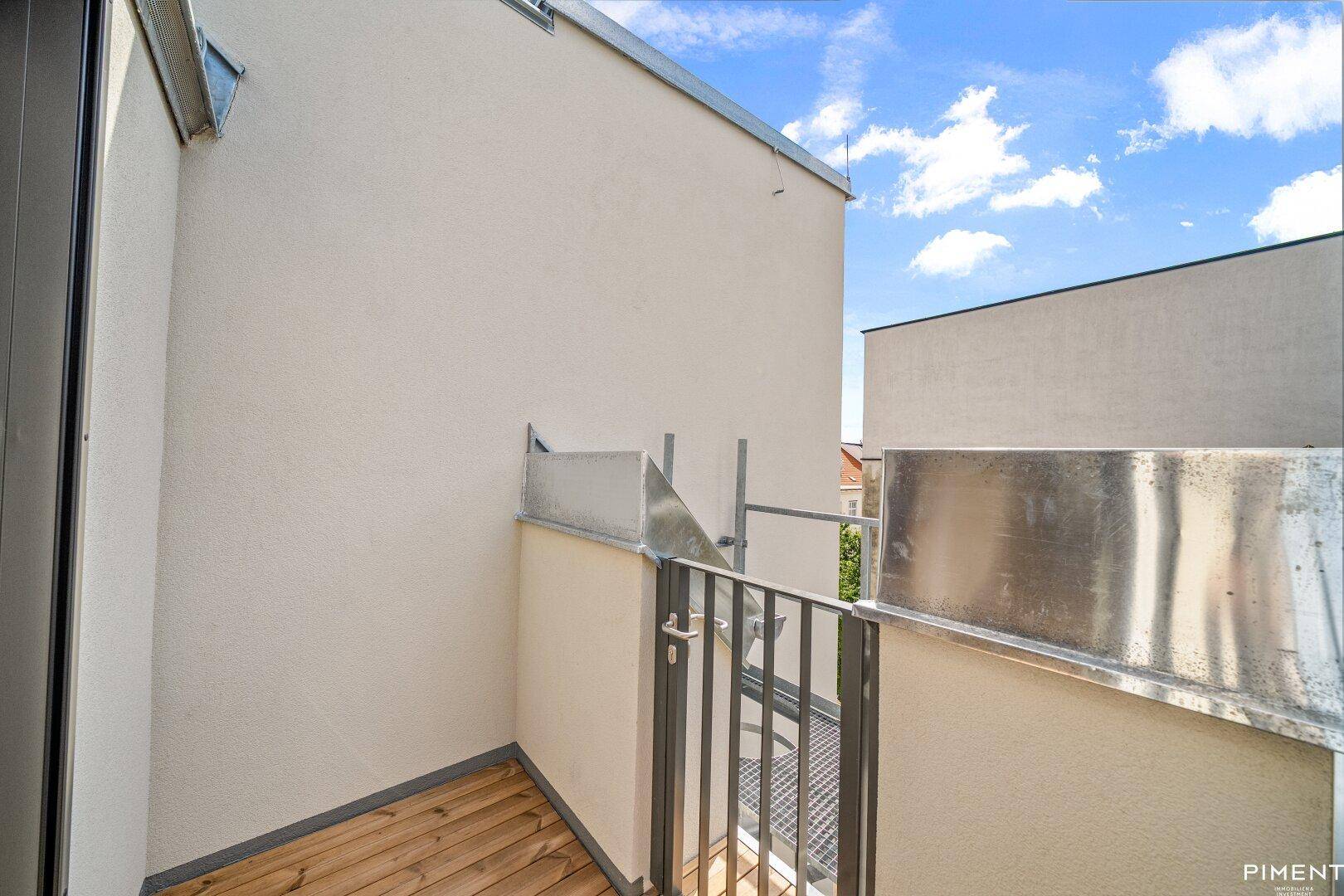 Kleiner Balkon mit Holzboden und Metallgeländer, ideal für eine kurze Auszeit im Freien.