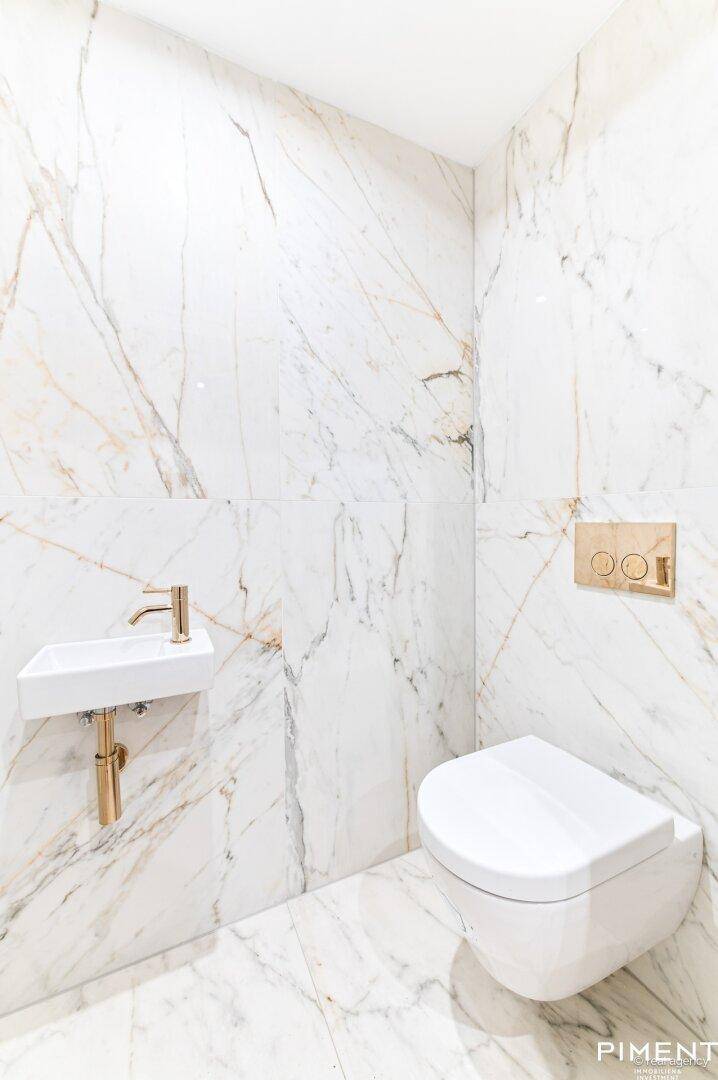 Modernes Gäste-WC mit Marmorfliesen, wandhängendem WC und kleinem Waschbecken.