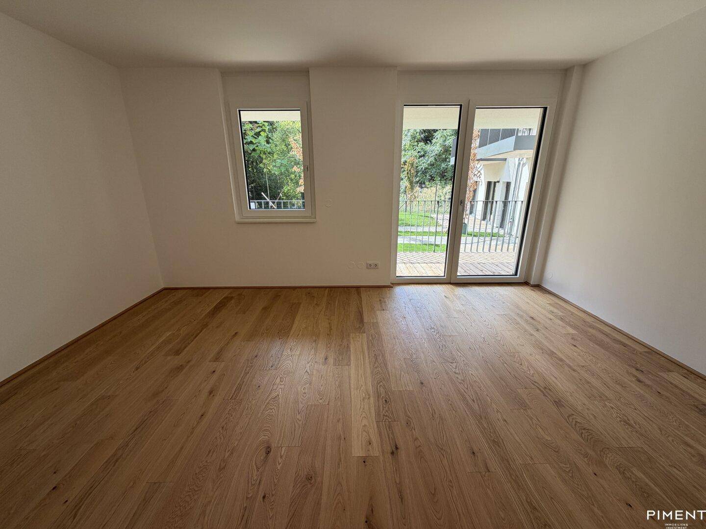 Helles Zimmer mit Eichenparkettboden und großen Fenstern, die viel Tageslicht hereinlassen.