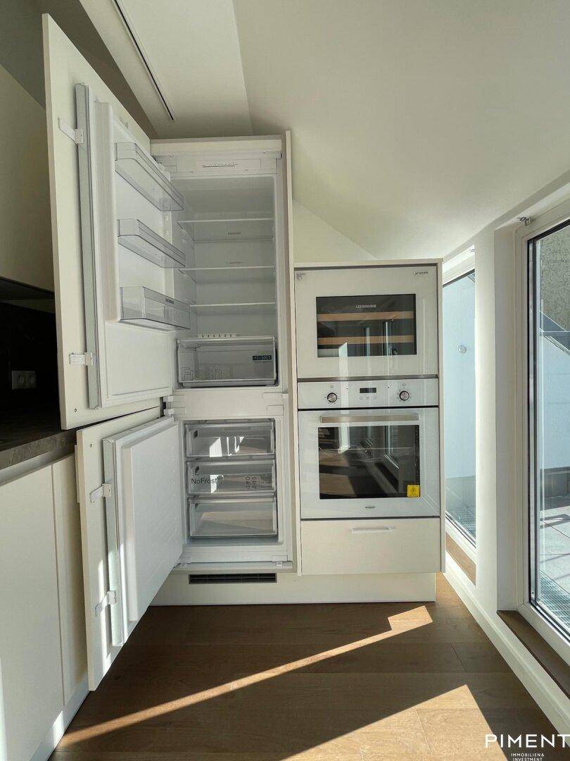 Integrierter Kühlschrank, Backofen und Weinkühler in der modernen, hellen Küche.