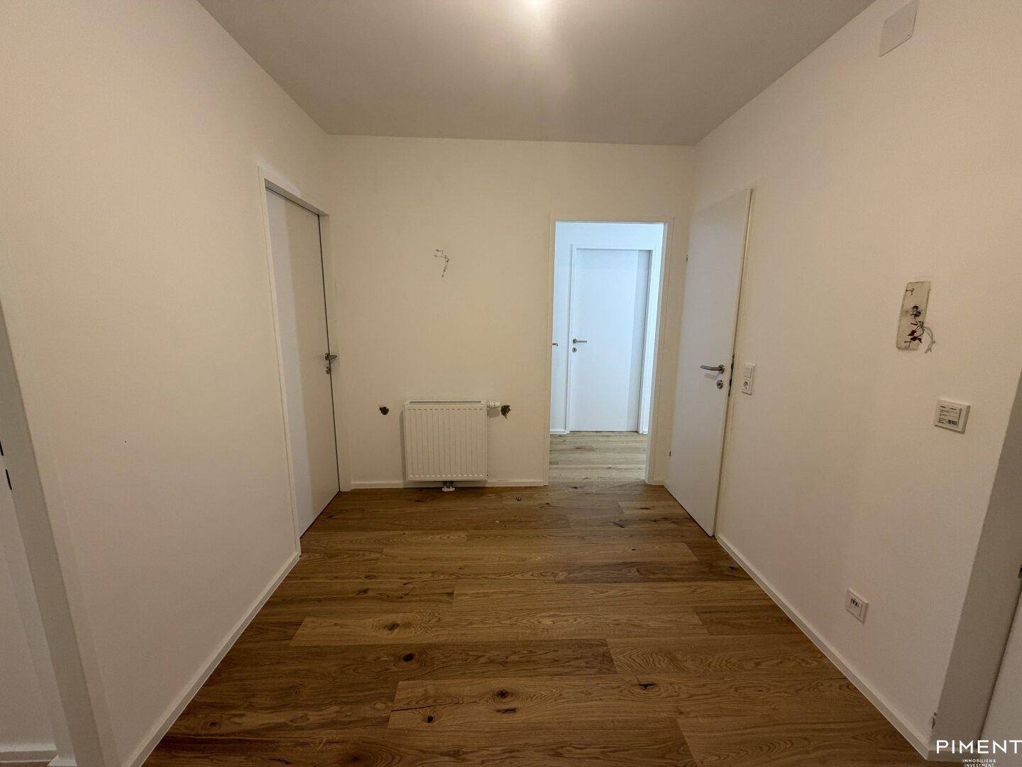 Heller Flur mit Holzparkettboden, der zu verschiedenen Räumen führt.
