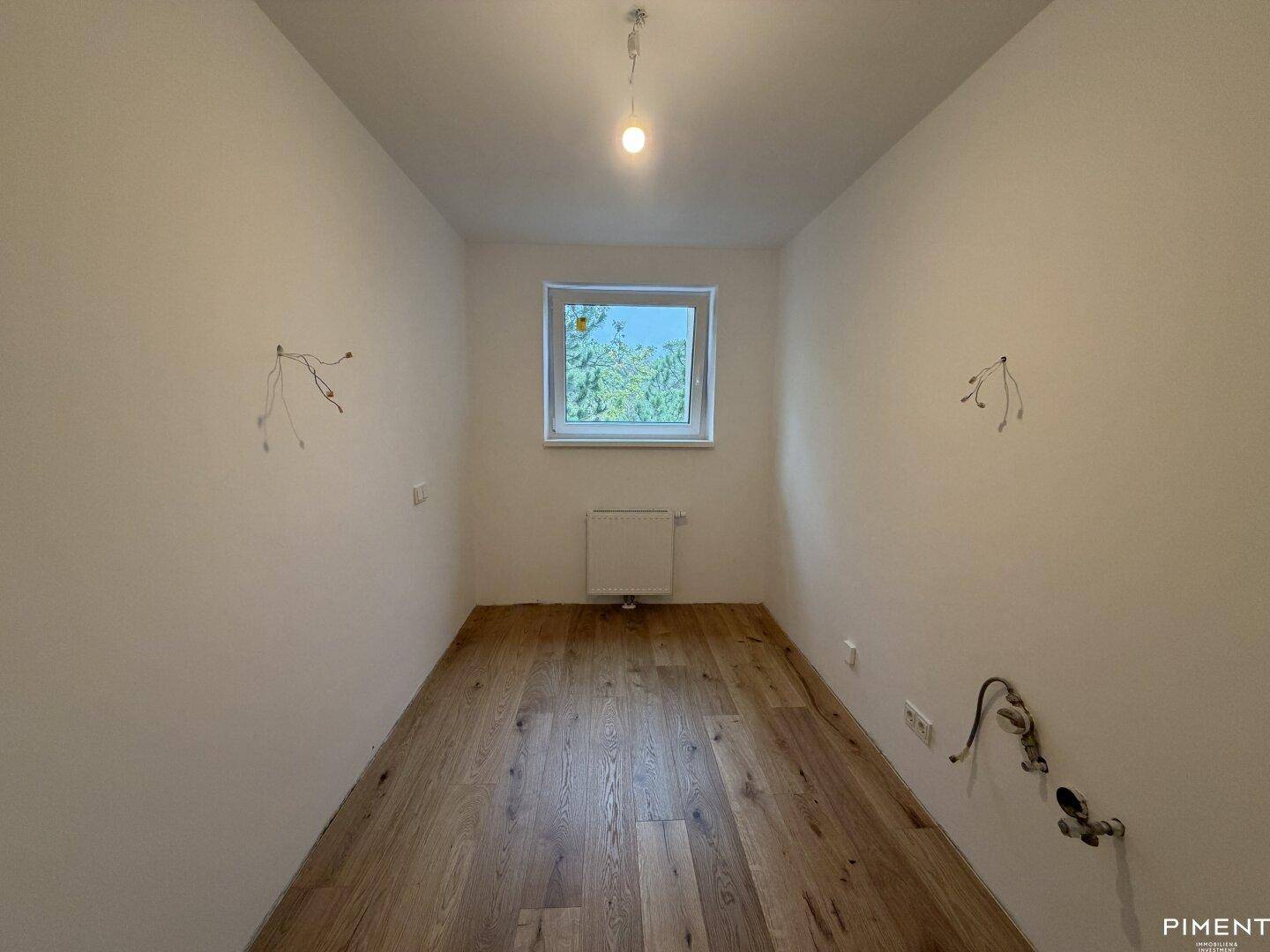 Kleiner Raum mit Holzparkettboden und Fenster, vielseitig nutzbar als Kinderzimmer oder Büro.