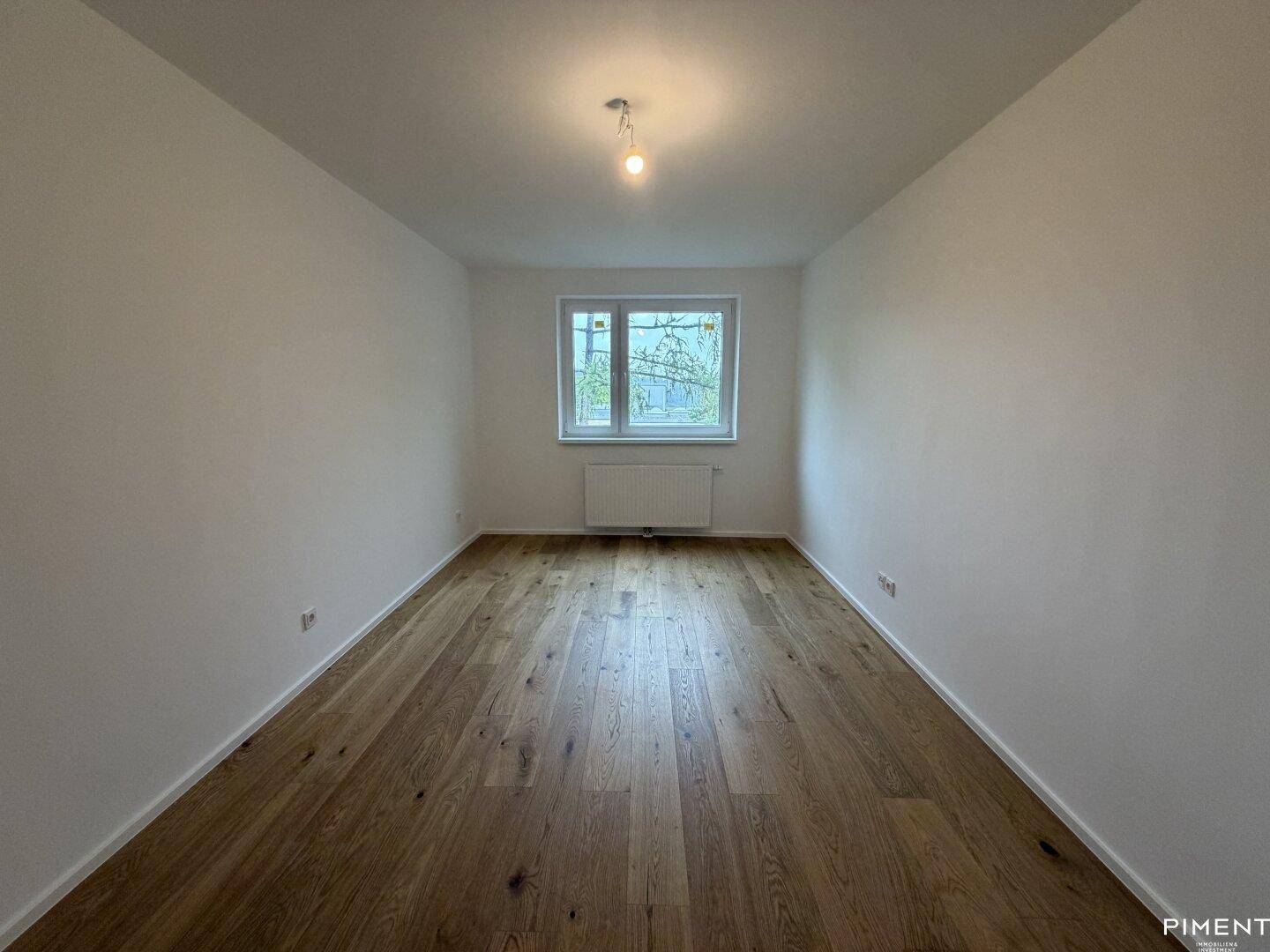 Drittes leeres Schlafzimmer mit Holzparkettboden und einem Fenster zur Belichtung.