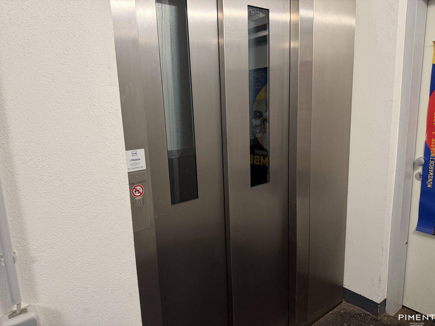 Moderner Aufzug mit Edelstahltüren in einem gemeinschaftlichen Flurbereich des Gebäudes.