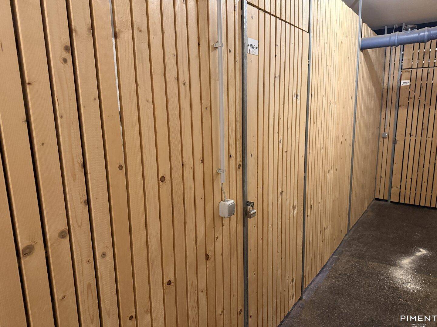 Reihe von Kellerabteilen mit Holztüren und individuellen Schlössern in einem Gemeinschaftskeller.