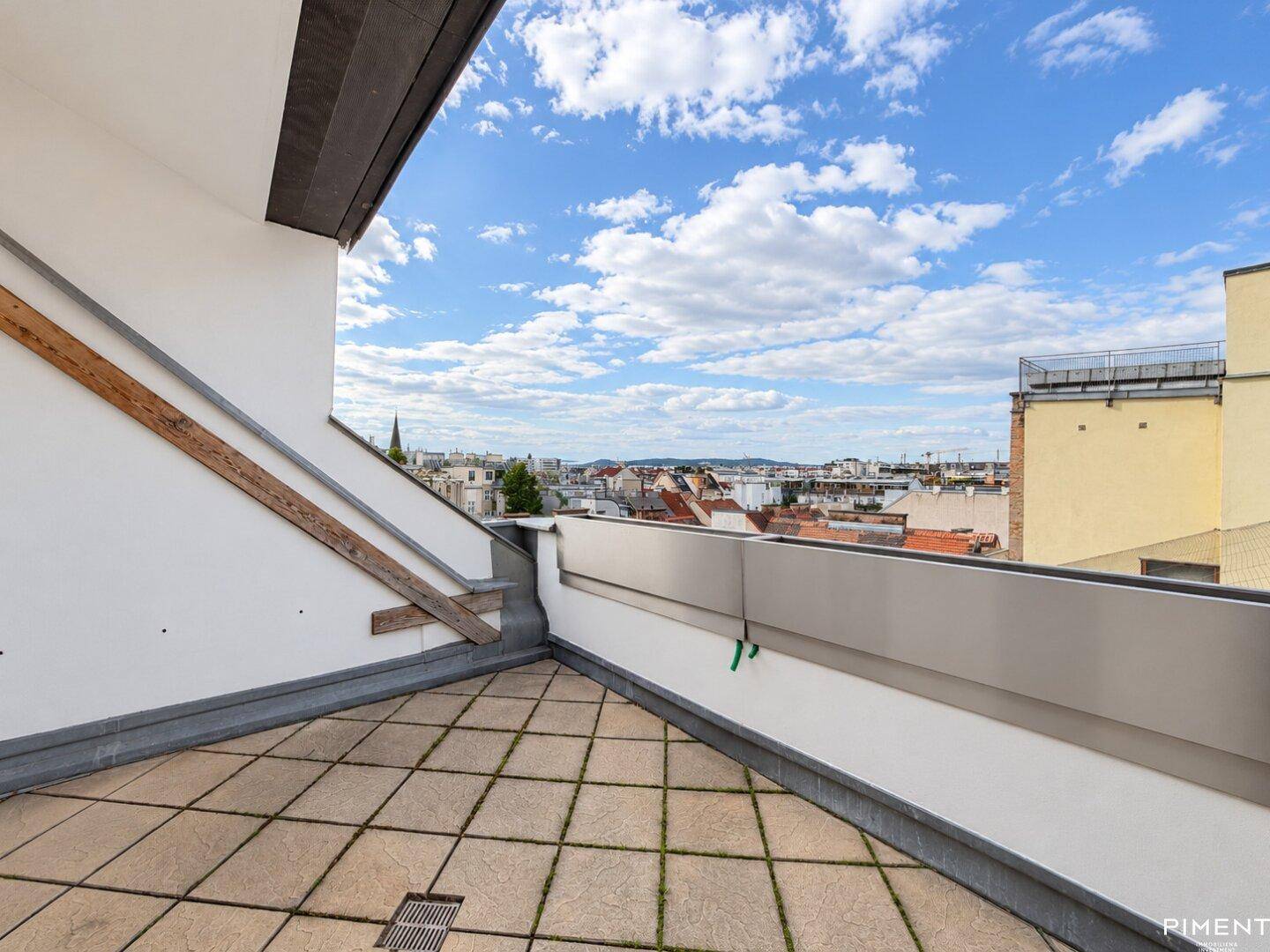 Dachterrasse mit Fliesenboden und weitem Blick über die Stadtlandschaft.