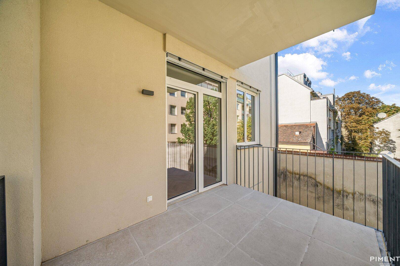 Geräumiger Balkon mit Fliesenboden und Blick auf die umliegenden Gebäude der Stadt.