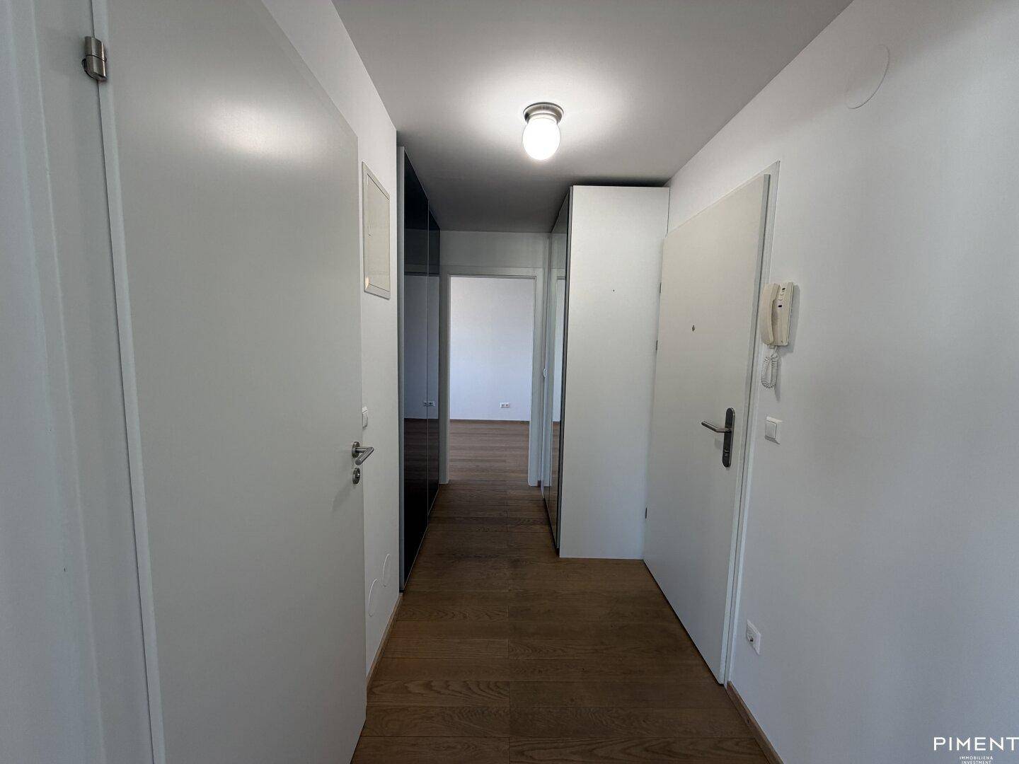 Heller Flur mit Parkettboden und weißen Türen, der zu weiteren Räumen führt.