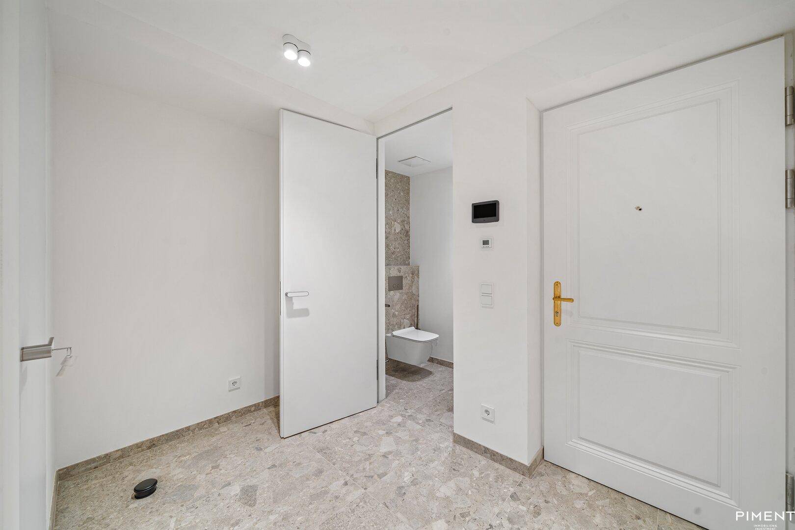 Eingangsbereich mit Fliesenboden und Blick in ein separates Gäste-WC.