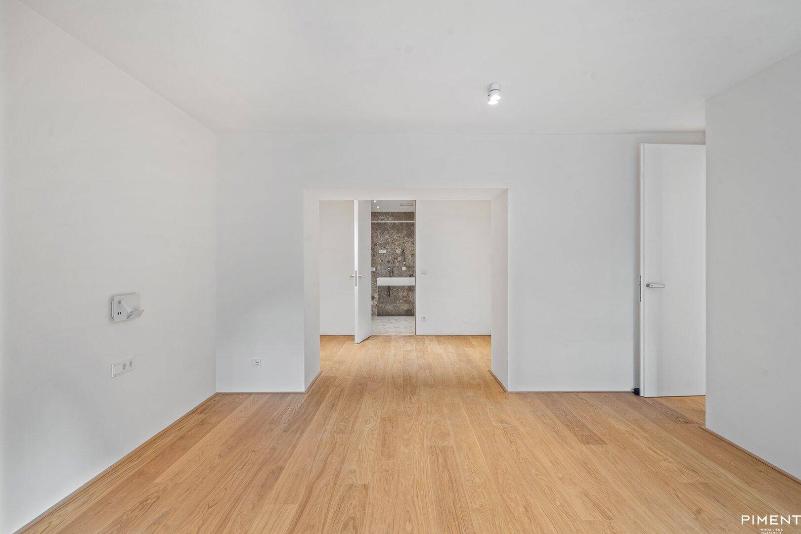 Heller Raum mit Holzboden und offenem Zugang zu einem modernen Badezimmer.
