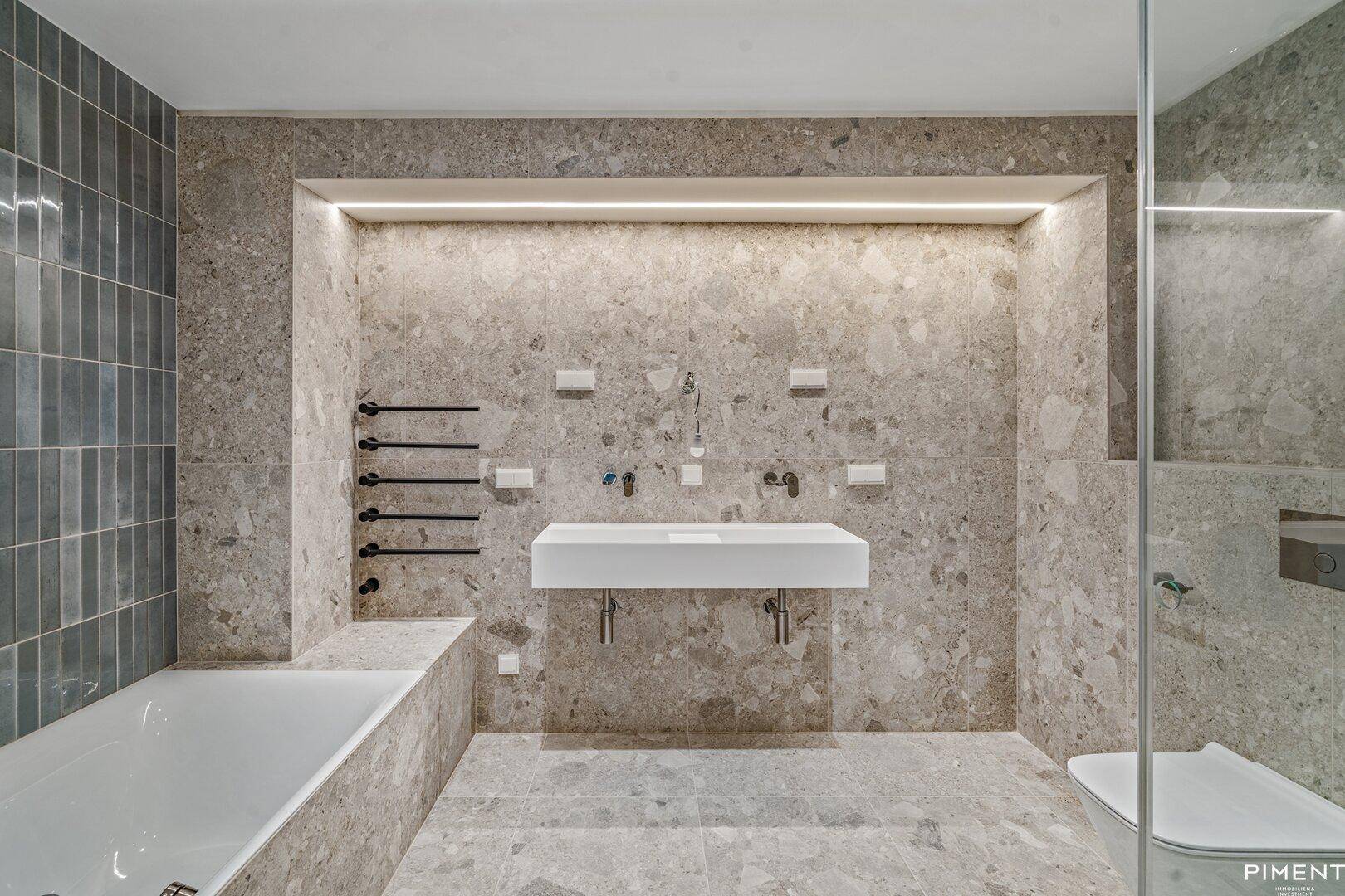 Modernes Badezimmer mit großformatigen Fliesen, Badewanne und separater Dusche.