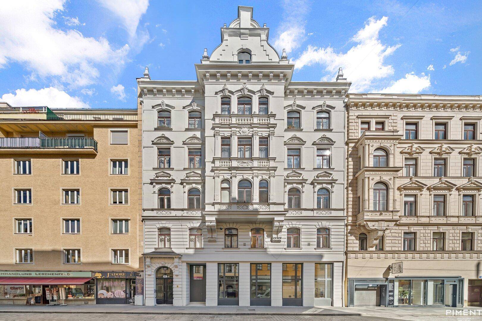 Historische Gebäudefassade mit reich verzierten Details und großen Fenstern zur Straße.