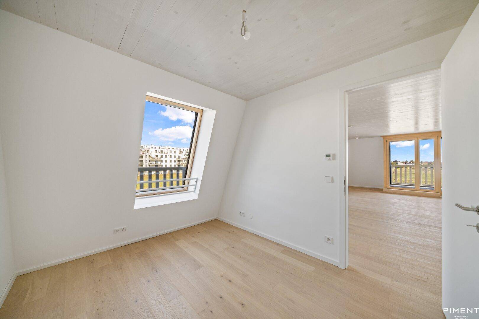Lichtdurchflutetes Schlafzimmer mit Holzboden und Blick auf die umliegende Landschaft.