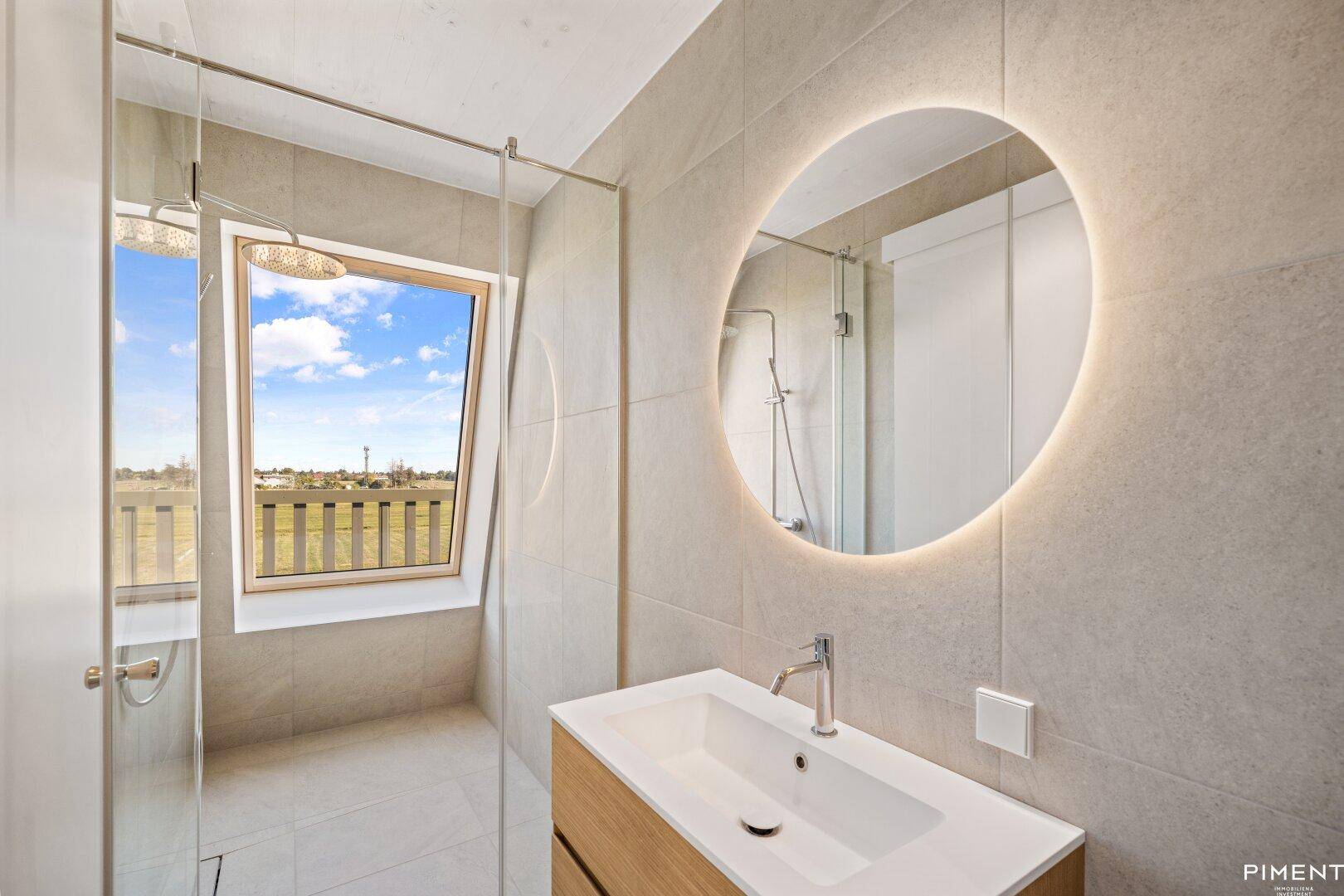 Modernes Badezimmer mit großer Dusche, beleuchtetem Spiegel und Dachfenster.