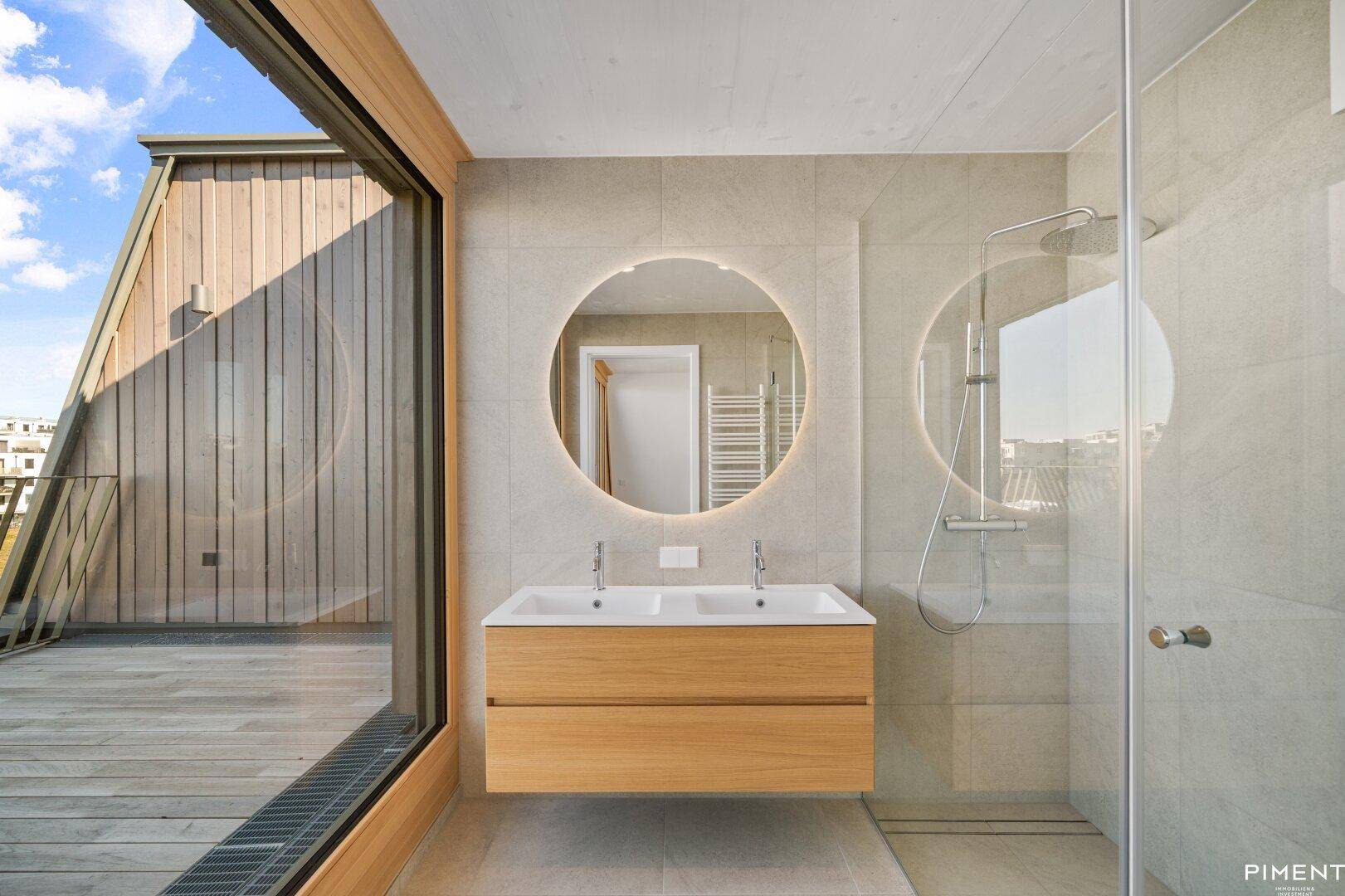 Modernes Badezimmer mit Doppelwaschbecken, beleuchtetem Spiegel und ebenerdiger Dusche.