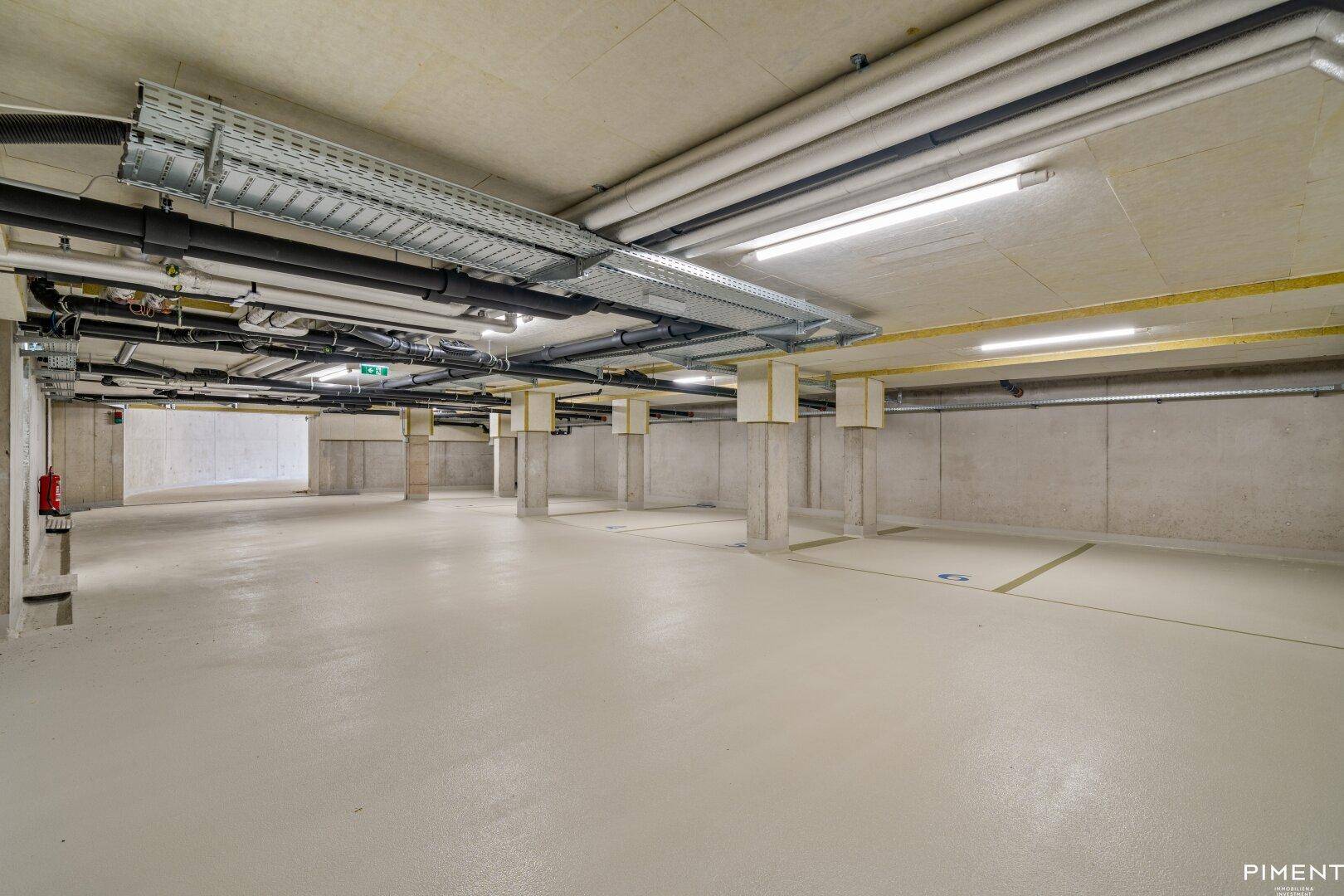 Geräumige und helle Tiefgarage mit Betonstützen und sauberem Boden.