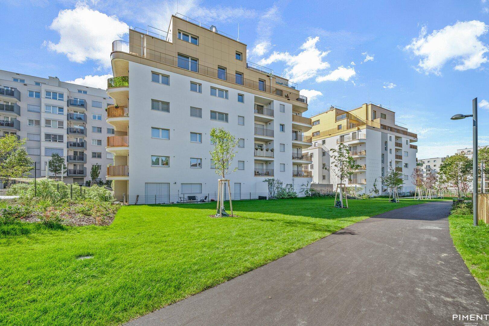 Mehrere moderne Wohngebäude mit Balkonen und weitläufigen Rasenflächen in einer neuen Siedlung.