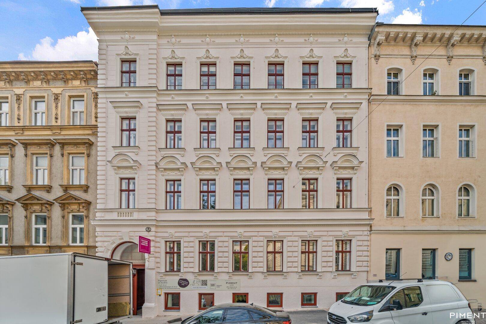Klassische Altbaufassade mit vielen Fenstern und dekorativen Elementen in hellem Farbton.