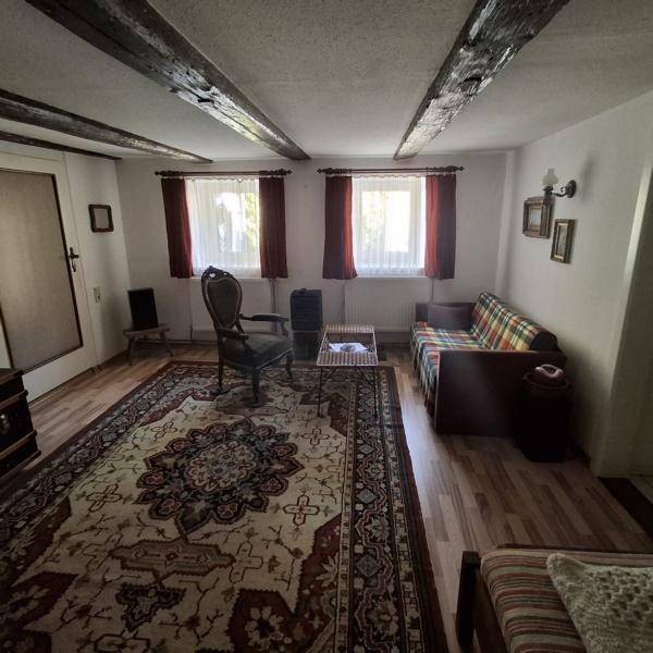 Gemütliches Wohnzimmer mit sichtbaren Holzbalken, Parkettboden und traditioneller Einrichtung.