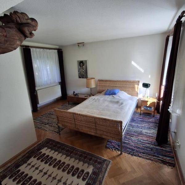 Helles Schlafzimmer mit Parkettboden, großem Bett und einem Teppich.