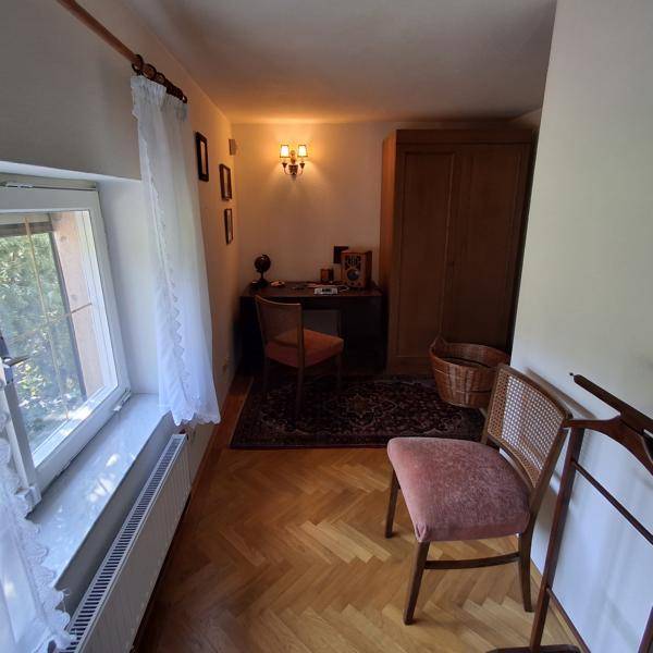 Kleines Arbeitszimmer mit Schreibtisch, Stuhl und Holzschrank.