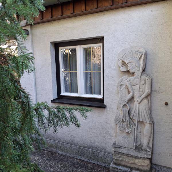 Fenster mit dunklem Rahmen und einer dekorativen Steinstatue an der Hauswand.
