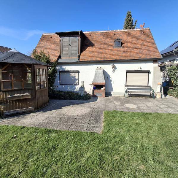 Gepflegter Gartenbereich mit Rasenfläche, Pavillon und gemauertem Grillplatz am Haus.