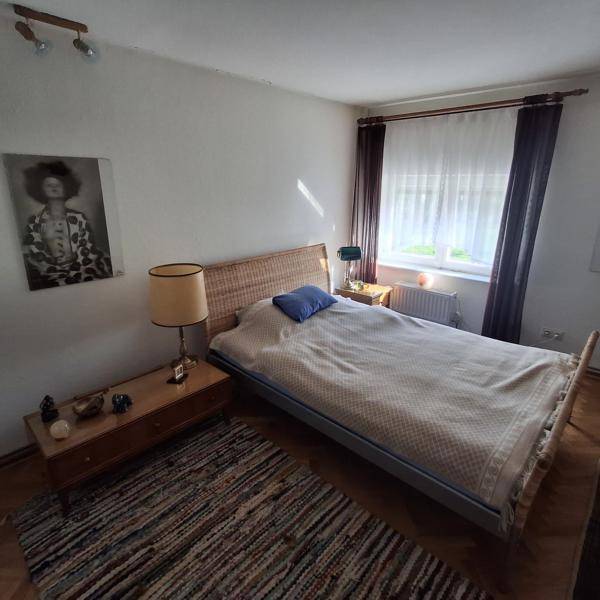 Schlafzimmer mit Doppelbett, Nachttischen und Fischgrätparkettboden.