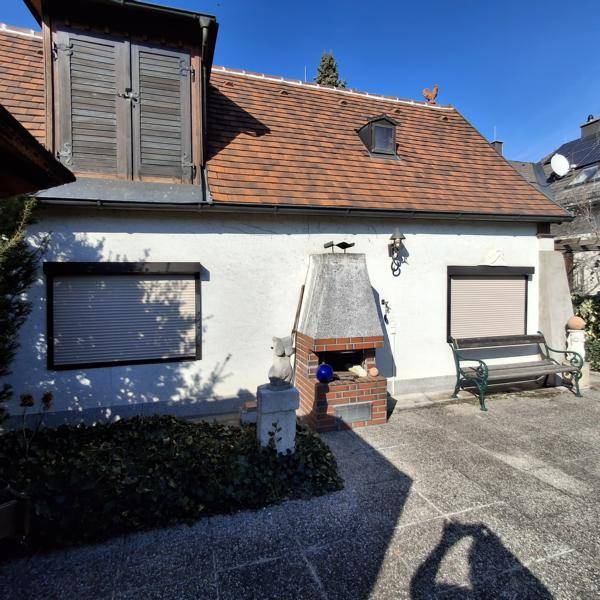 Sonnige Terrasse mit Außenkamin und Sitzbank, ideal für gemütliche Stunden im Freien.
