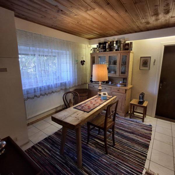 Gemütlicher Essbereich mit rustikalem Holztisch, Stühlen und einer Holzdecke.