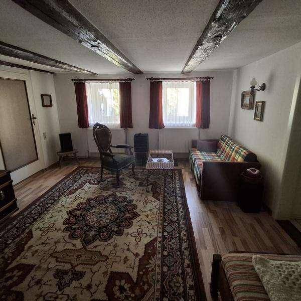 Gemütliches Wohnzimmer mit Holzbalken, Teppich und einem karierten Sofa.