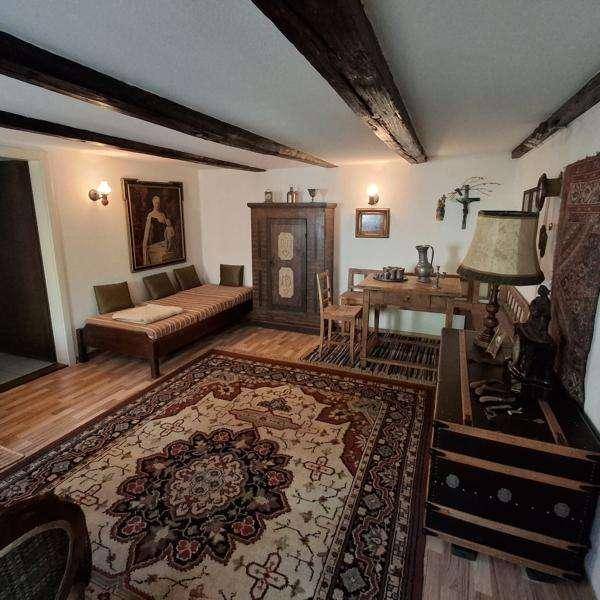Gemütliches Wohnzimmer im Landhausstil mit Holzbalken, Teppich und traditionellen Möbeln.
