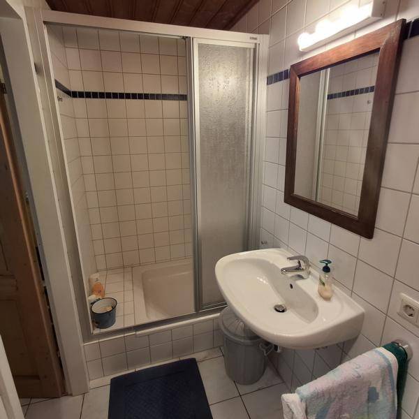 Funktionales Badezimmer mit Duschkabine, Waschbecken und weißen Fliesen.